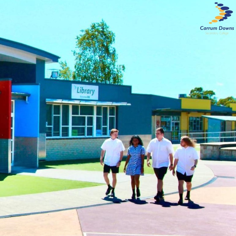 4 students walking outside within the school grounds.