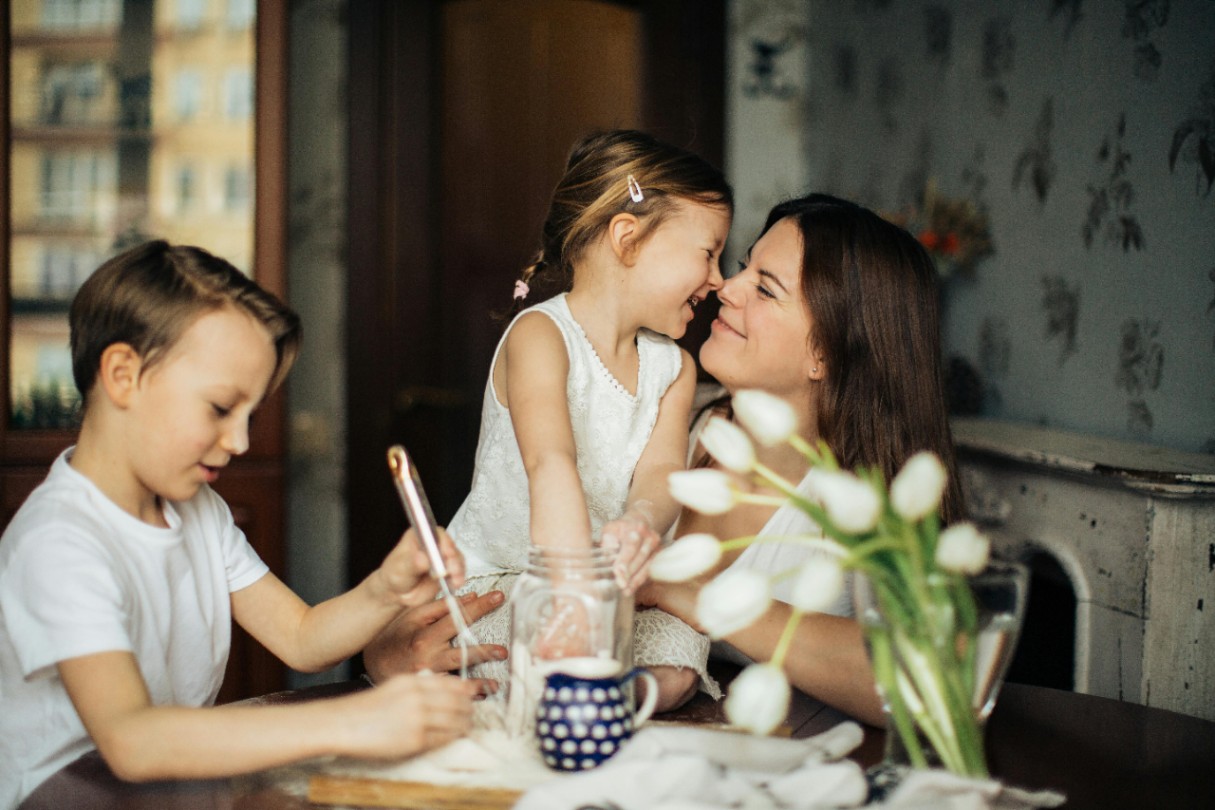 Woman and two kids at a table smiling 