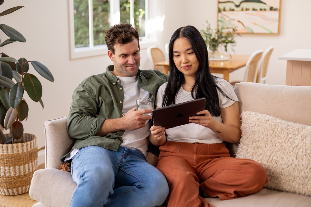 Man and woman looking at a tablet together on the couch