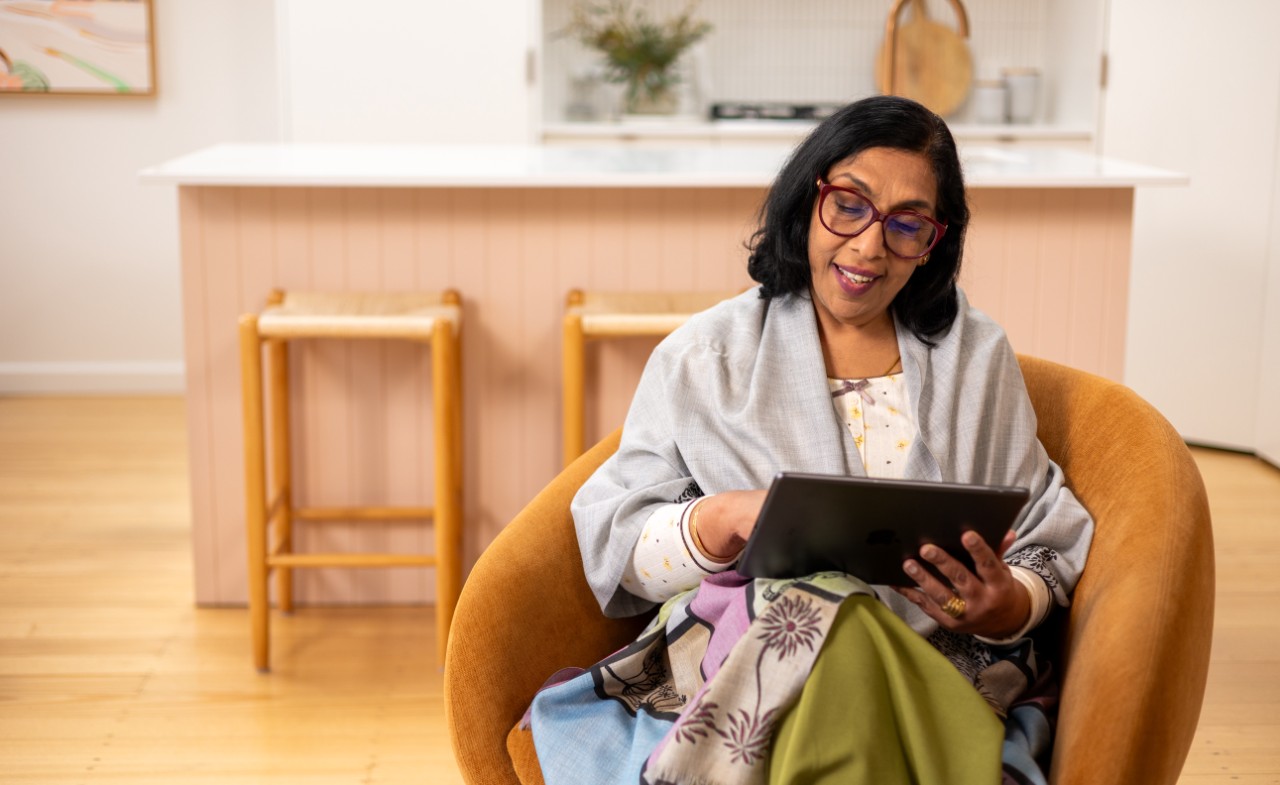 Woman sitting on a lounge chair looking a tablet. 